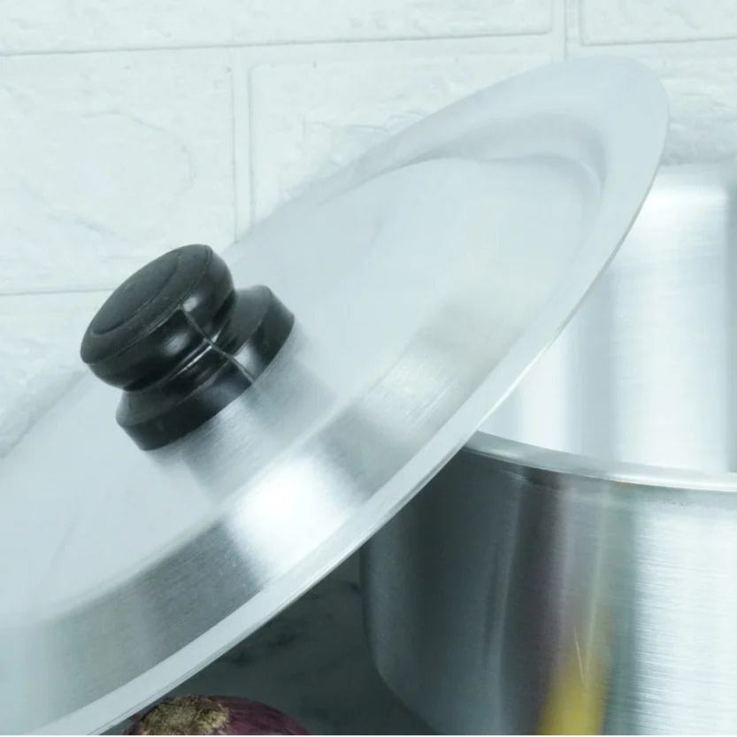 Clear glass lid on a pot with a black handle against a tiled wall background
