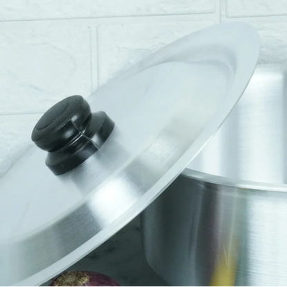 Clear glass lid on a pot with a black handle against a tiled wall background