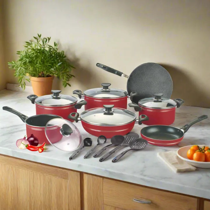 Set of red cookware with black handles on a kitchen counter.