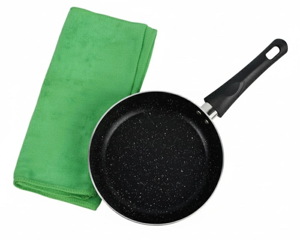 Black speckled frying pan with a green towel on a white background