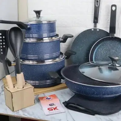 Set of blue speckled cookware with lids on a marble surface, including pots, pans, and utensils.
