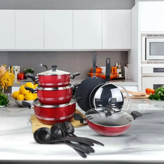Red cookware set on a kitchen counter with various kitchen items in the background.