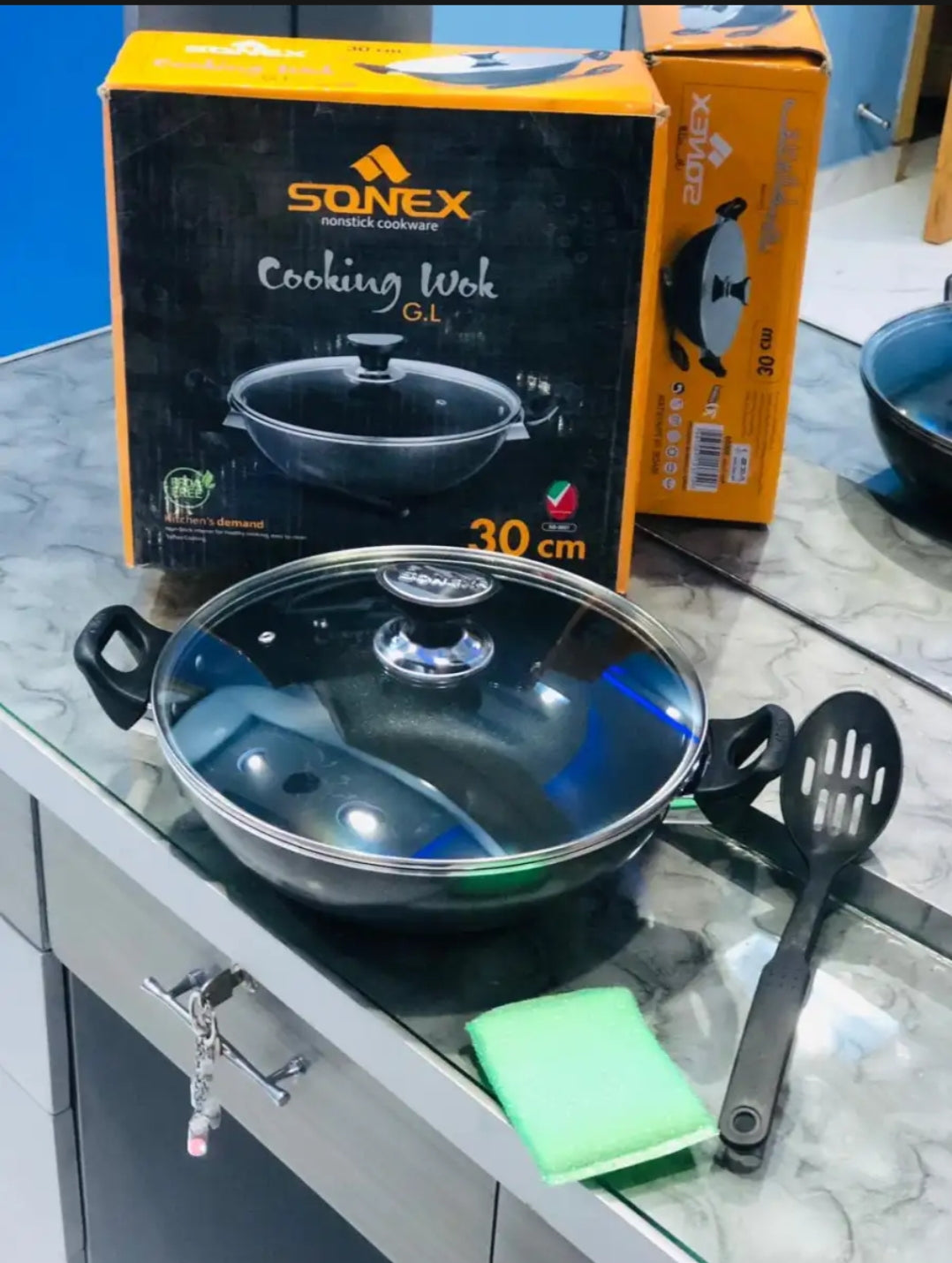 Cooking wok with lid on a countertop next to Sonex packaging