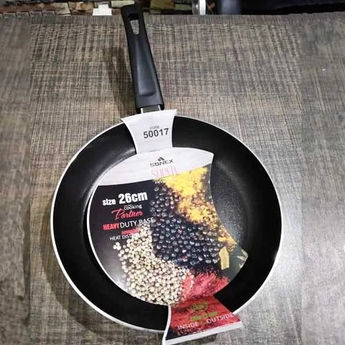 Black frying pan with a brand label on a wooden surface